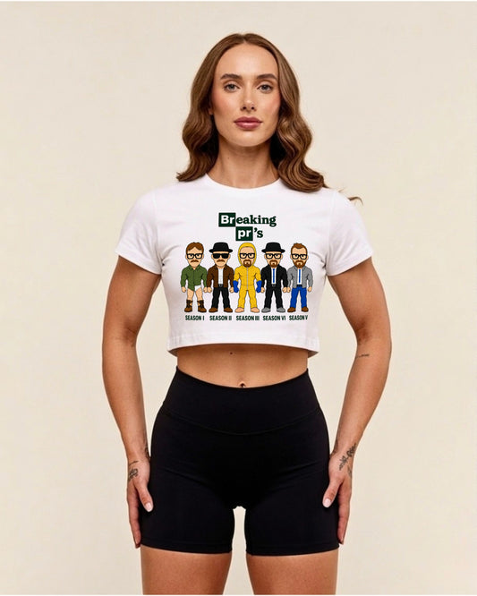White Breaking pr's oversized gym crop top, front view on a model: tile-style lettering above five cartoon characters in different outfits with season captions